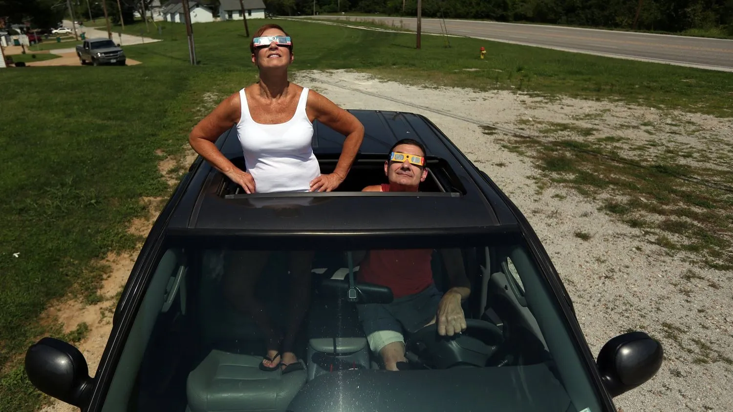 zwei Personen, die die Sonnenfinsternis von ihrem Auto aus beobachten. 
