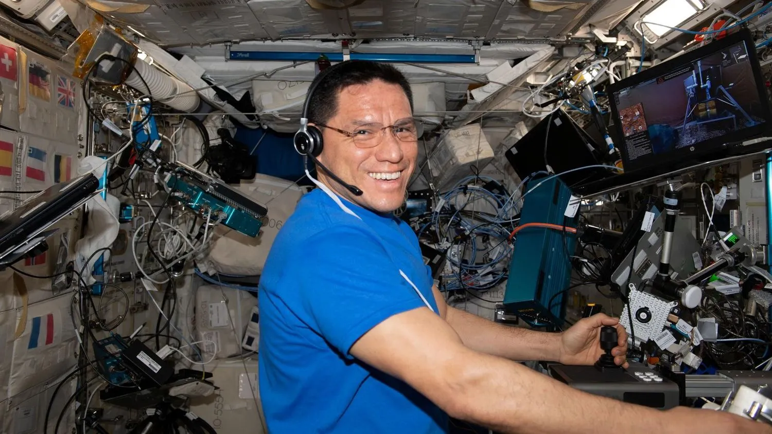 ein Astronaut, der in Spies schwebt, lächelt beim Hantieren mit Laborgeräten