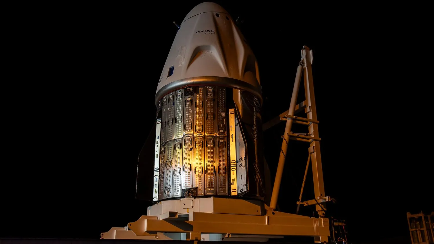 eine weiße SpaceX-Kapsel ist in einem großen, dunklen Raum zu sehen.