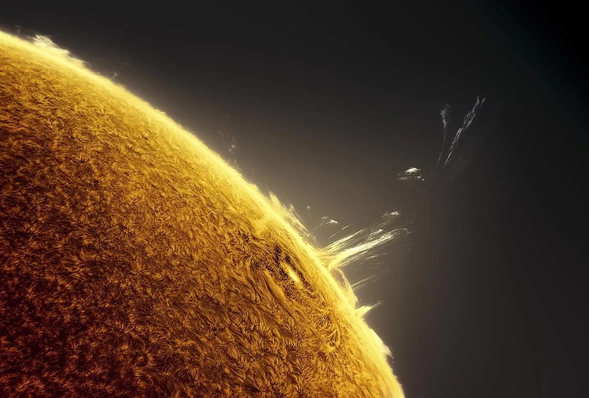 Eine Ecke der Sonne sitzt unten links im Bild, während die engen Schleifen einer Sonneneruption knapp über den Sonnenhorizont hinausragen.