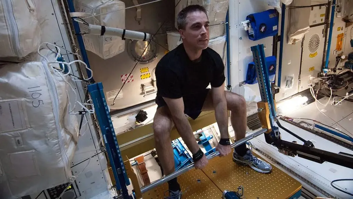 Astronaut hockt über einer Gewichthebe-Maschine