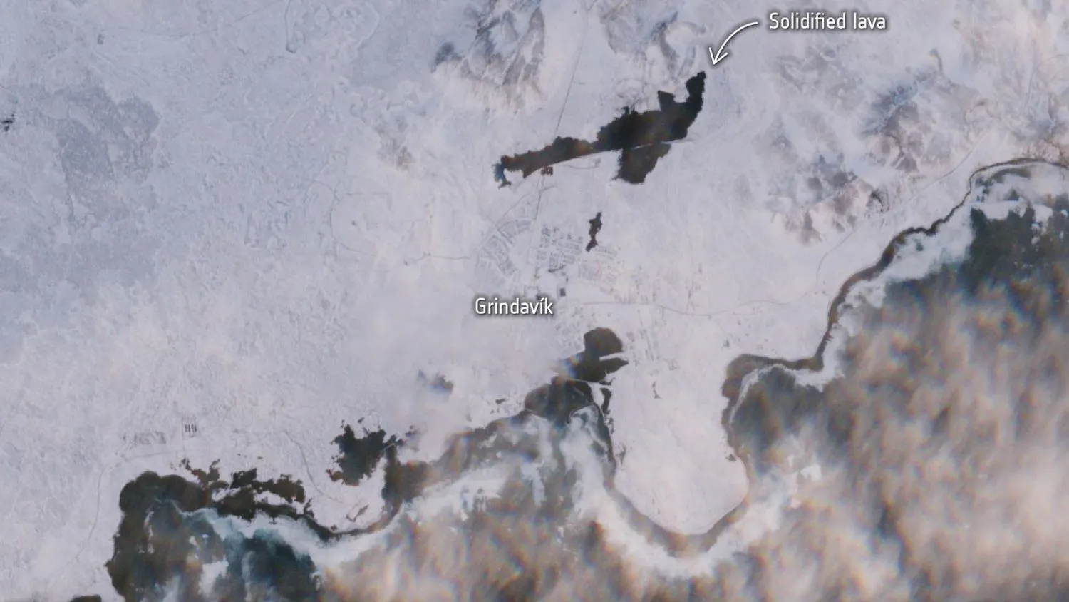 Satellitenfoto einer eisigen Landschaft mit einem dunklen Fleck, der auf einen frisch erstarrten Lavastrom hindeutet.