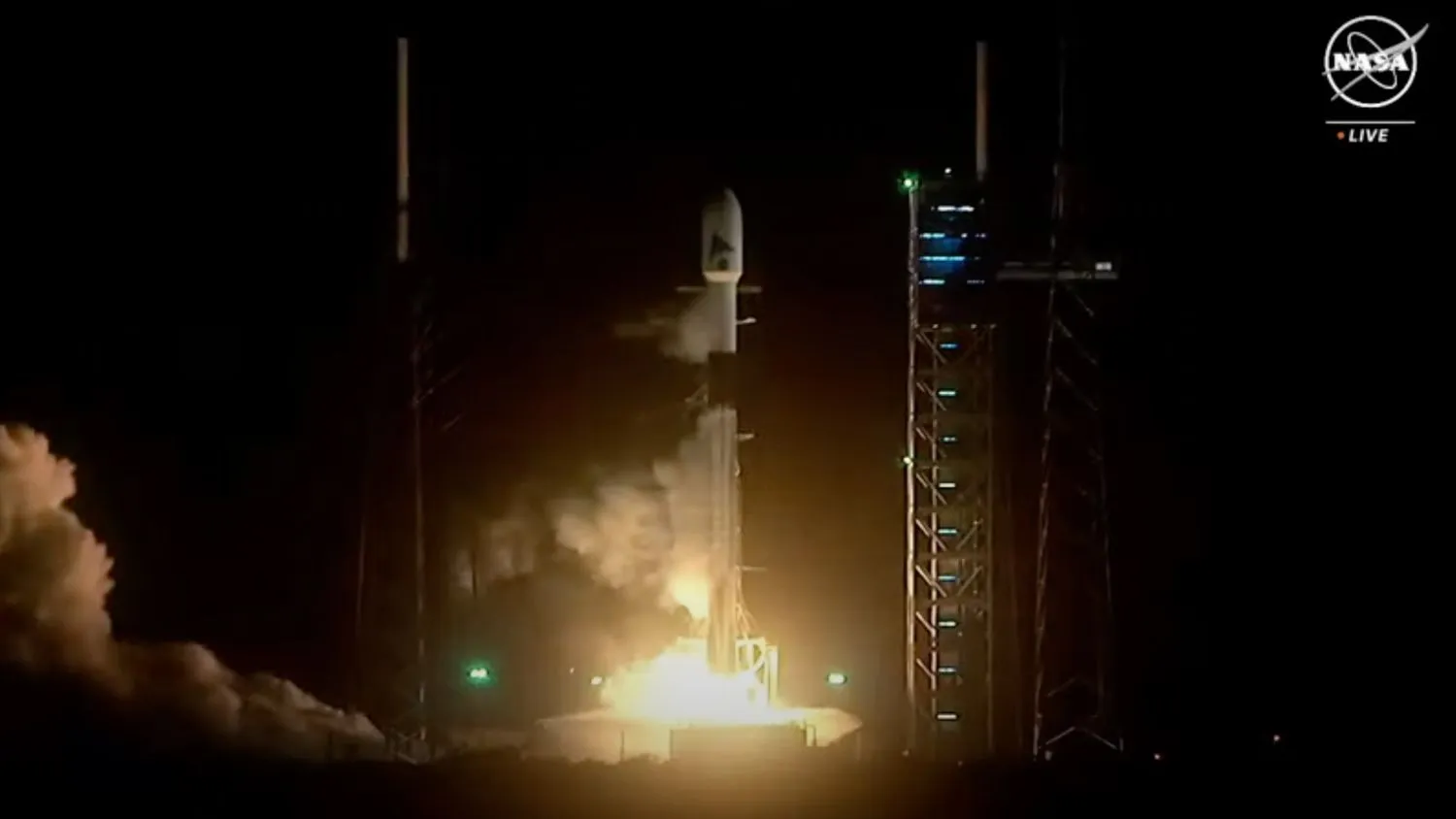 eine schwarz-weiße SpaceX Falcon 9 Rakete startet in den Nachthimmel.