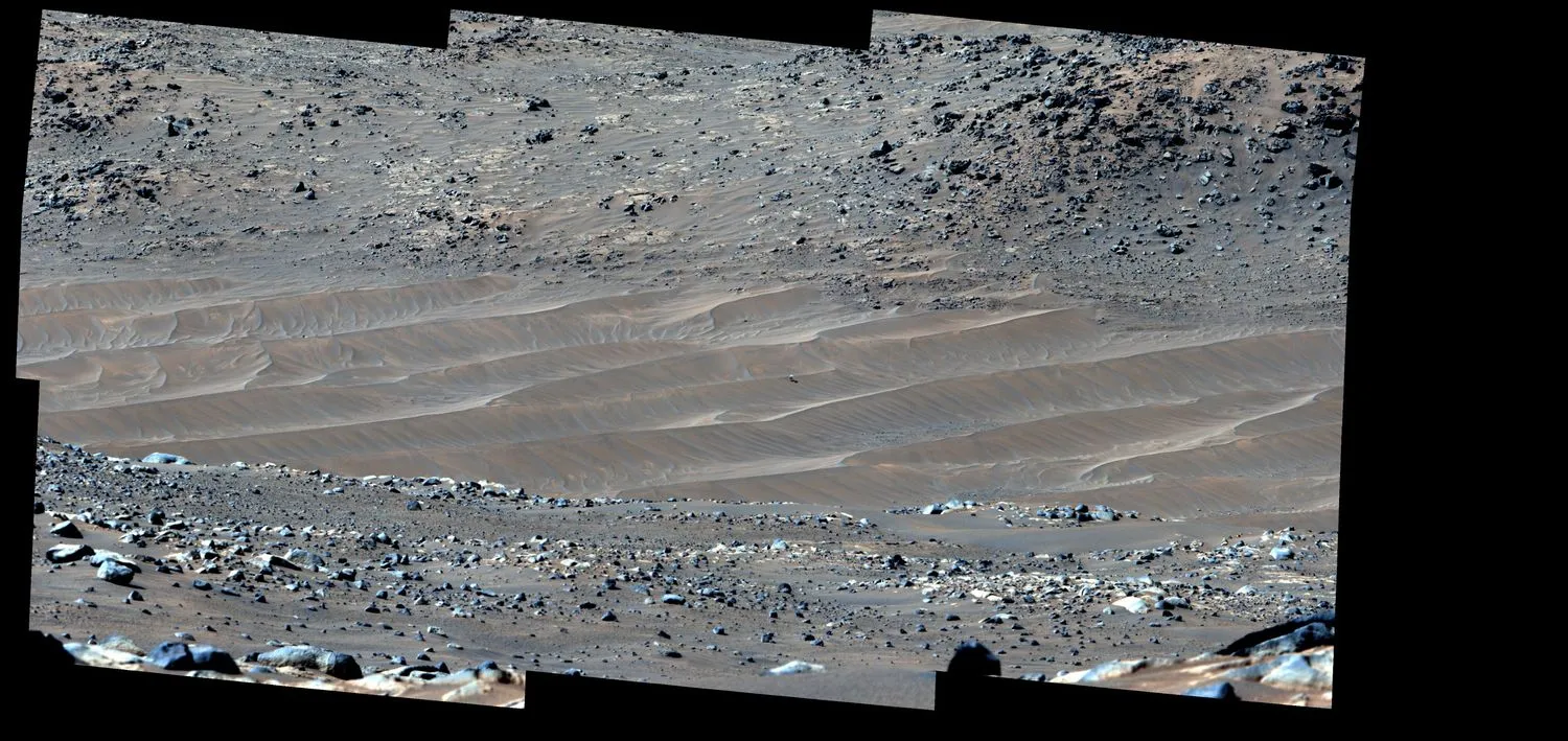 ein panoramafoto von grau-roten sanddünen. auf einem ist eine winzige hubschrauberdrohne zu sehen, weit in der ferne