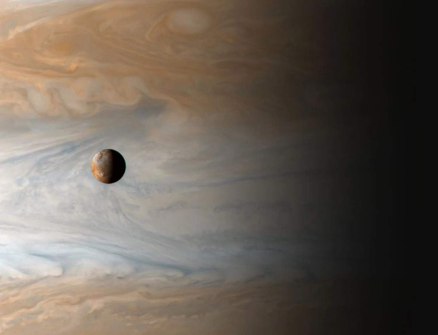 ein kleiner Mond vor dem wirbelnden Hintergrund des Jupiters
