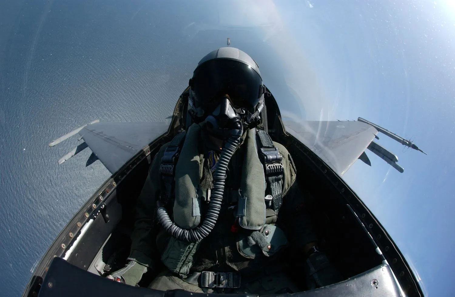Eine Person im Cockpit eines Kampfjets mit Blick auf den Ozean darunter