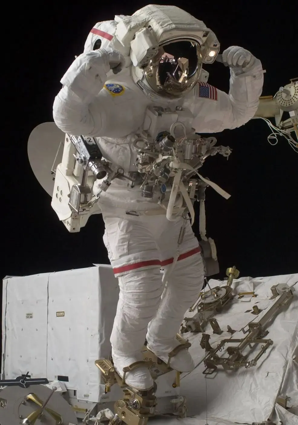 Astronaut in einem Raumanzug mit den Füßen in Fußfesseln. Der Astronaut hebt die Hände über den Kopf