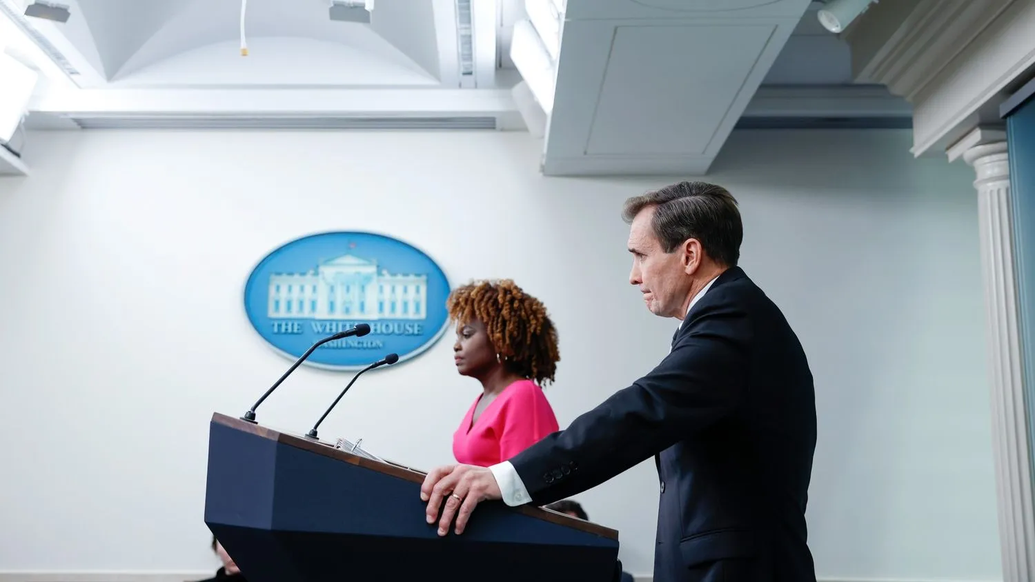 eine Person im Anzug steht an einem Rednerpult unter einem Schild mit der Aufschrift Weißes Haus