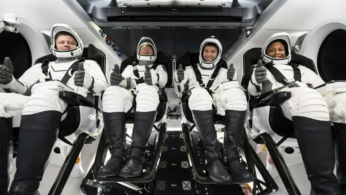 Vier Astronauten in weißen Startanzügen geben Daumen-nach-oben-Zeichen.