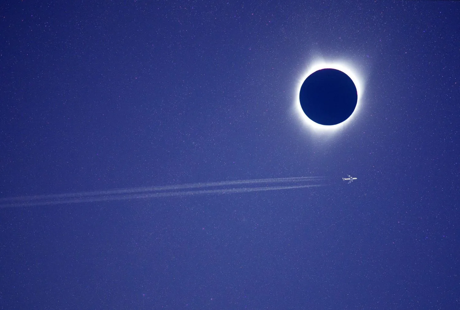 ein Flugzeug fliegt durch den Himmel direkt neben dem Mond, der die Sonne am Himmel verdunkelt