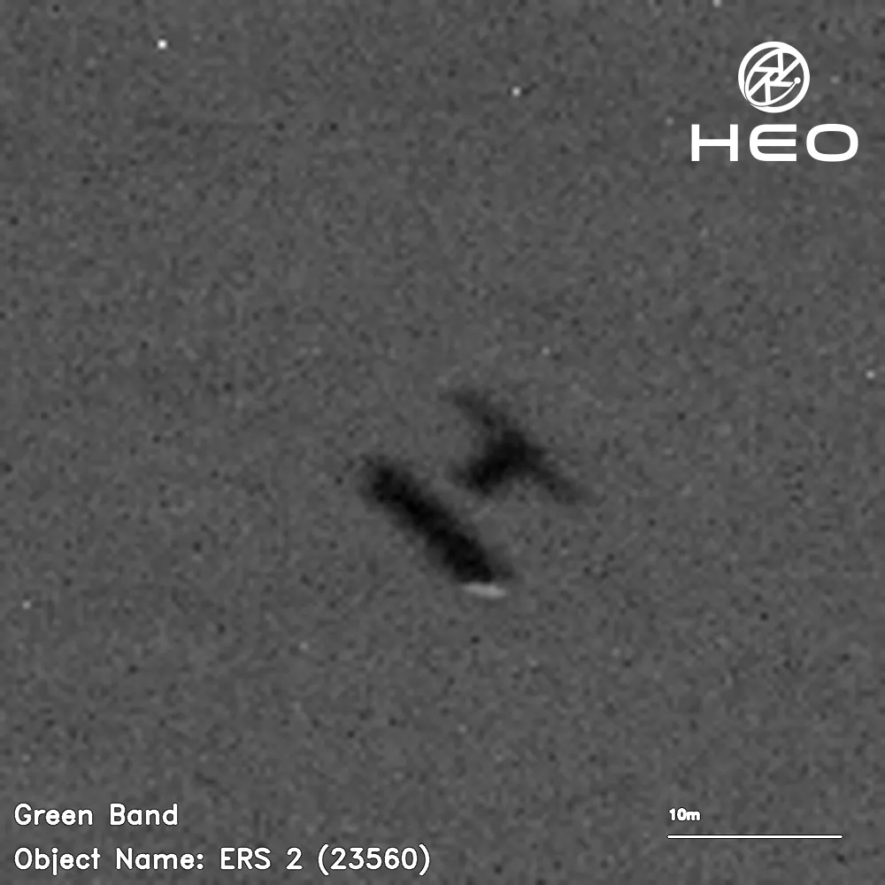 ein verschwommenes Schwarz-Weiß-Bild eines H-förmigen Satelliten vor einem Hintergrund von ein paar Dutzend Sternen