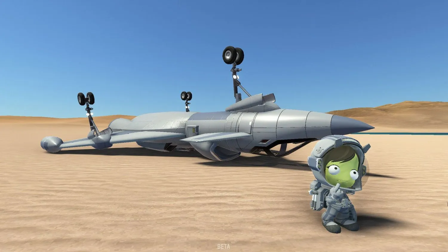 Ein grüner Humanoid steht in einem Raumanzug in einer Sandlandschaft, hält sich einen Finger ans Kinn und schaut verwirrt. Hinter ihr liegt ein Düsenflugzeug auf dem Kopf. Der Himmel ist blau.