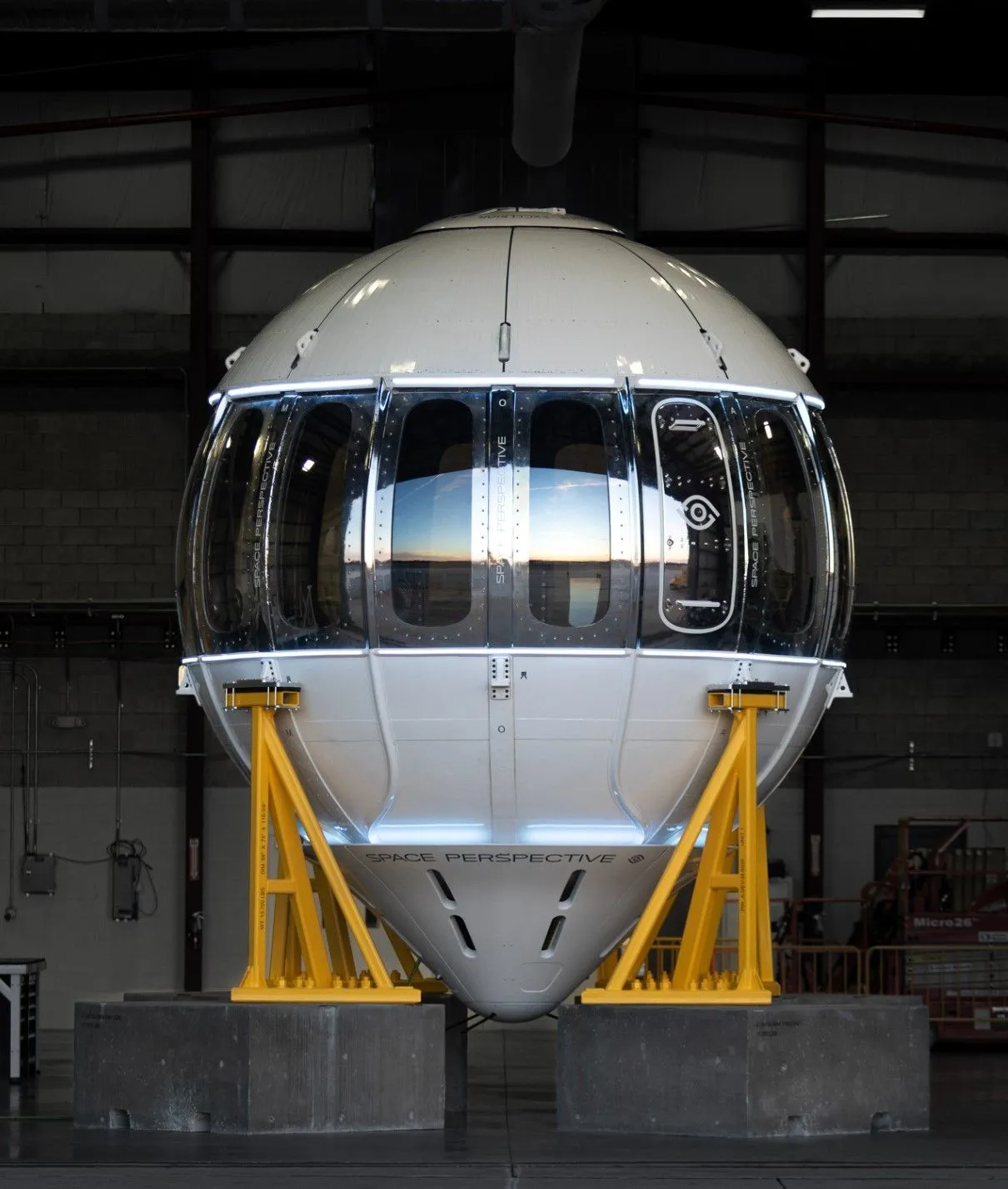 eine kugelförmige Metallkapsel mit Fenstern in einem Hangar