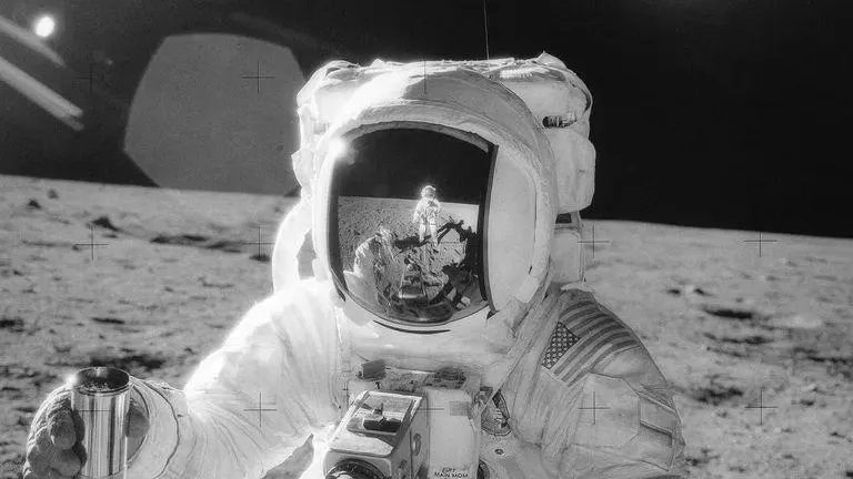  Einer der Astronauten auf der Mondoberfläche hält einen Behälter mit Monderde. Der andere Astronaut spiegelt sich in seinem Helm. Apollo 12 kehrte am 24. November 1969 sicher zur Erde zurück.