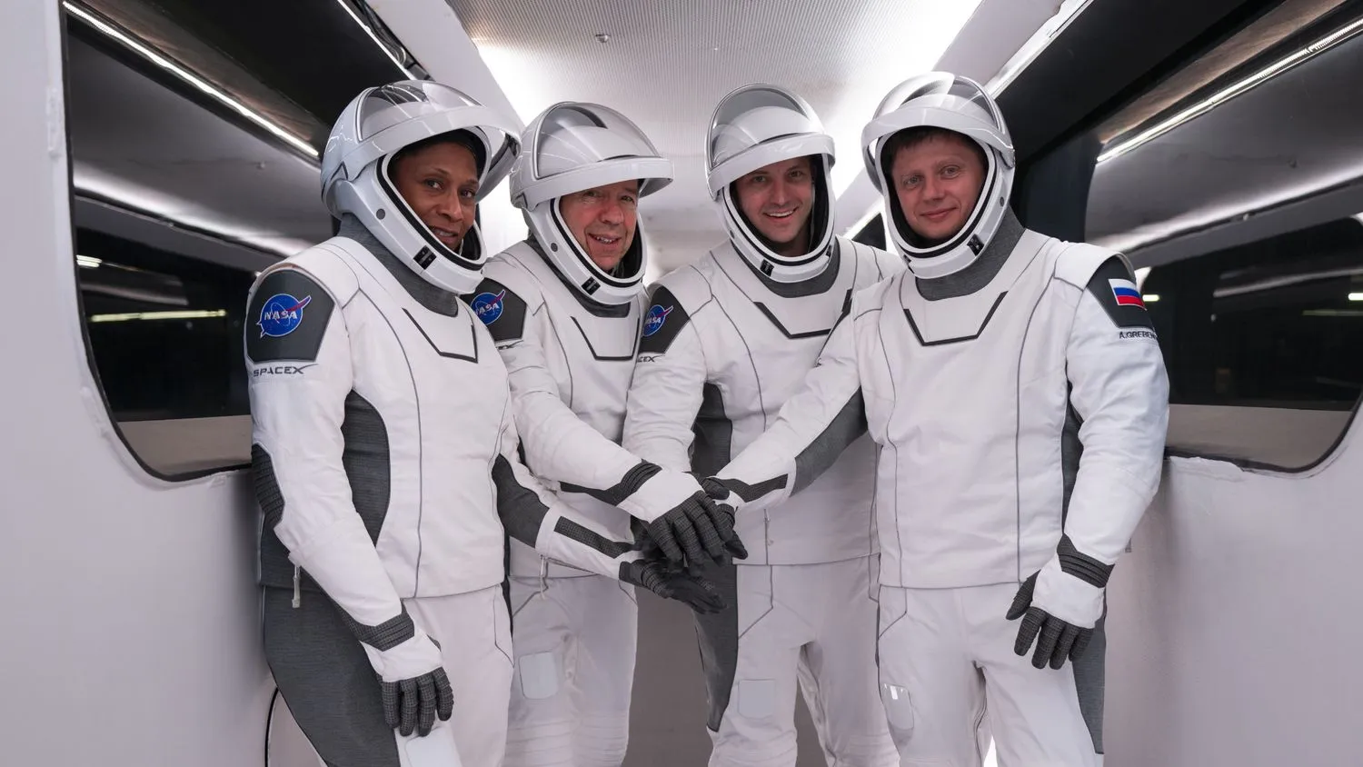 Vier Crew-8-Astronauten in weißen SpaceX-Raumanzügen mit verschränkten Armen vor dem Start.