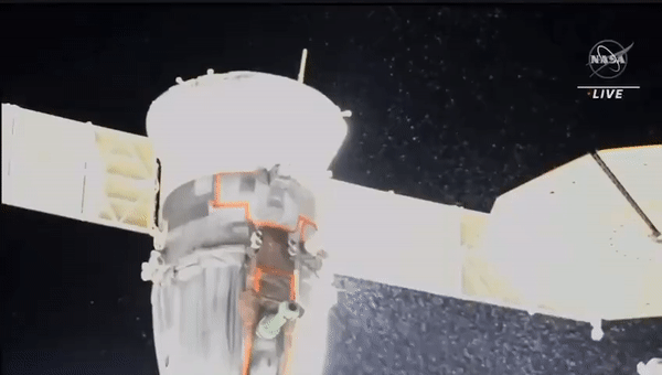 Vor der Schwärze des Weltraums im Hintergrund spritzt eine blasse Flüssigkeit kegelförmig aus einem weißen Zylinder