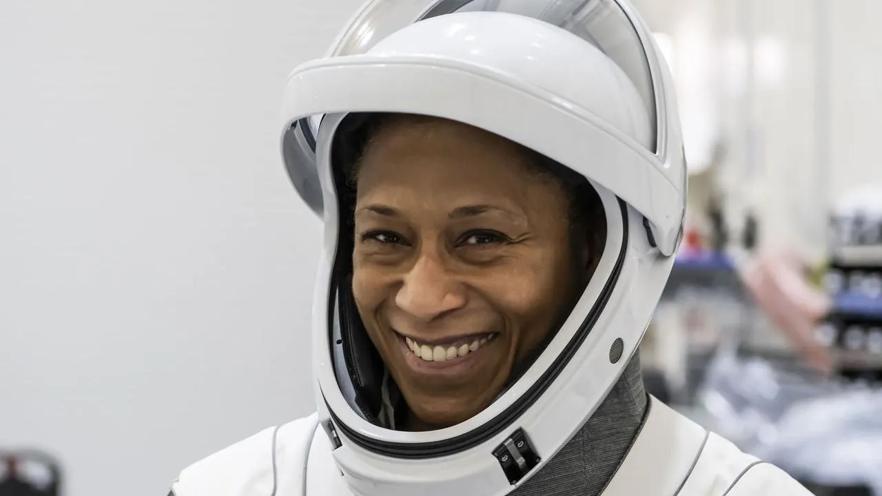 lächelnde Frau im Raumanzug mit Laborausrüstung weit im Hintergrund