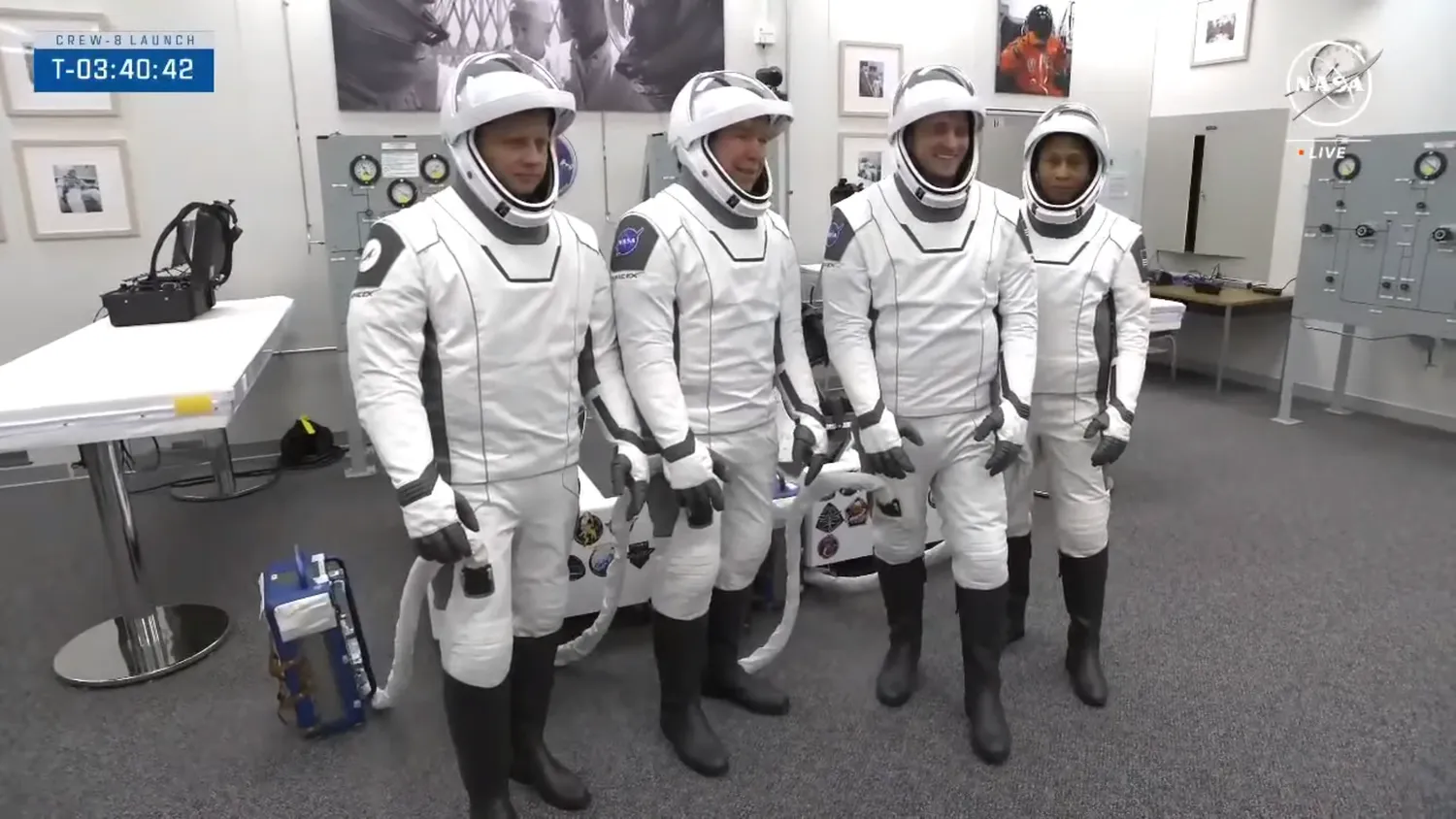 vier Astronauten posieren für ein Foto in weißem Raumanzug in einem Checkout-Raum