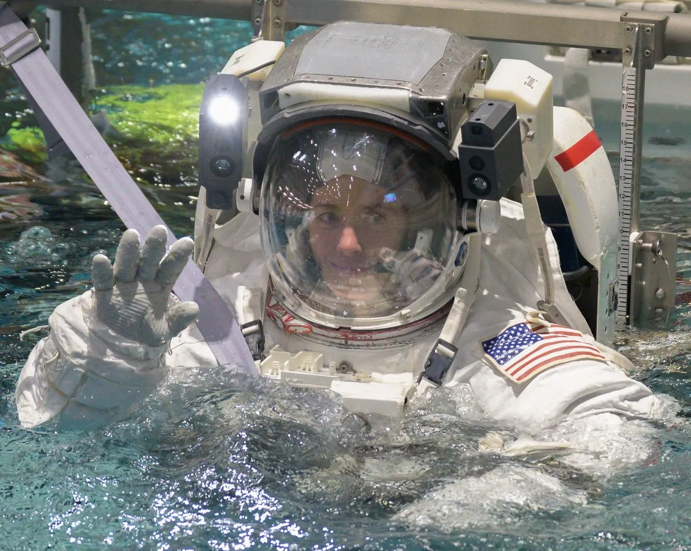 ein Astronaut in einem Raumanzug, der in einem Pool winkt