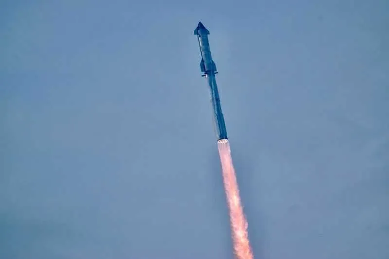 eine große silberne Rakete fliegt durch einen blauen Himmel über einer großen Feuerwolke