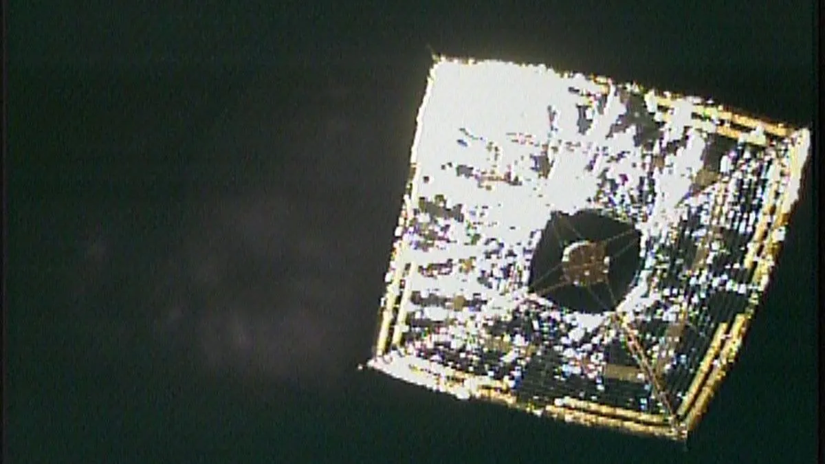 Foto eines silbern glänzenden, quadratischen Sonnensegels im tiefen Weltraum