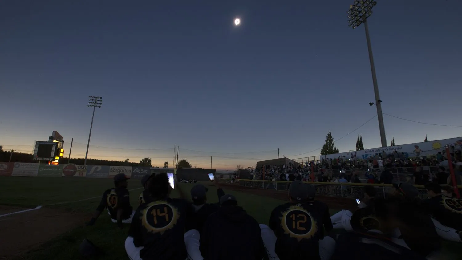 Menschenmengen und Spieler versammeln sich unten, um die Mondfinsternis über der Sonne zu beobachten. 