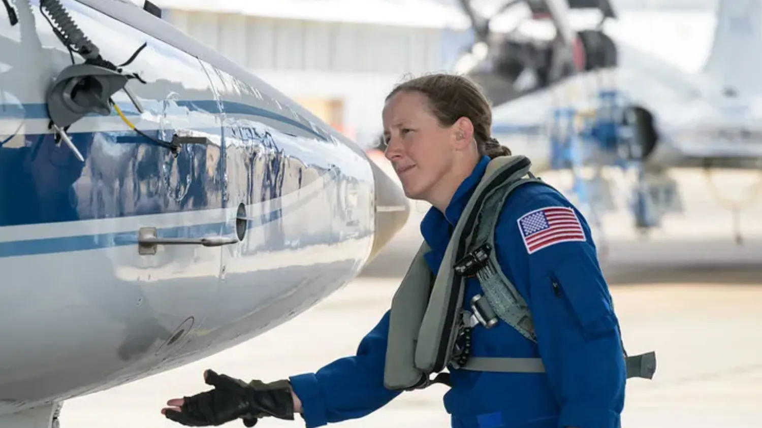 ein Astronaut im Fluganzug, der nach der Nase eines Flugzeugs greift
