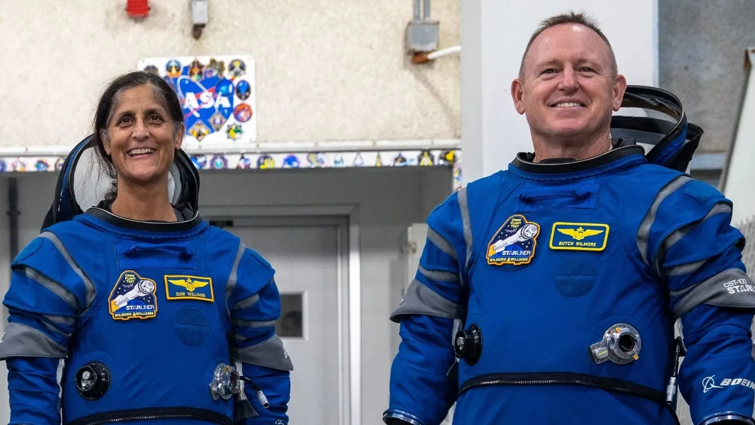 zwei Astronauten stehend und lächelnd in Raumanzügen und Helmen