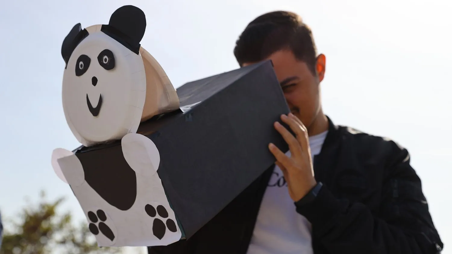 ein Mann schaut durch einen Lochprojektor, der wie ein Panda dekoriert wurde