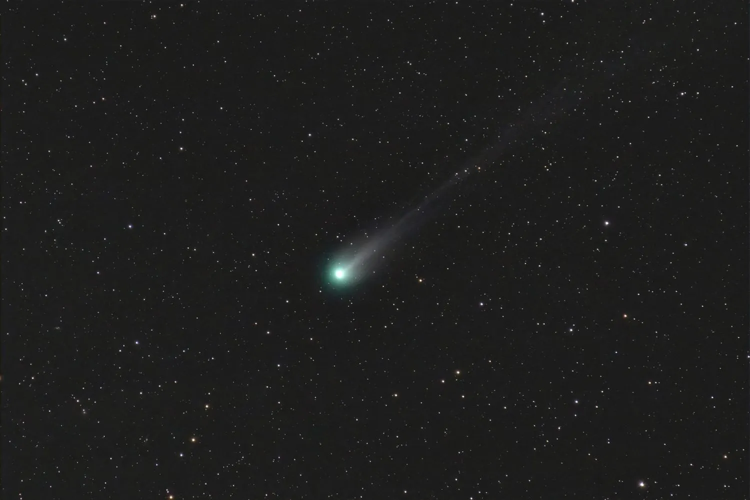 grün und weiß leuchtender Komet mit langem Schweif vor einem Sternenhintergrund