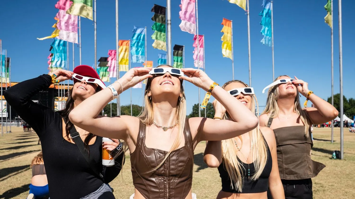 Vier Menschen blicken zu einer Sonnenfinsternis auf, während sie sich Papierbrillen vor die Augen halten