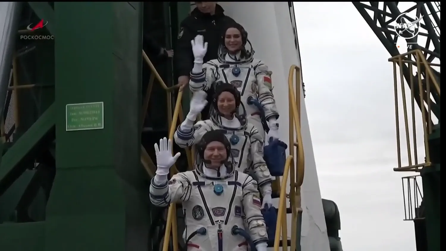 Drei Astronauten winken zum Abschied, während sie sich auf das Einsteigen in ihre russische Rakete vorbereiten.