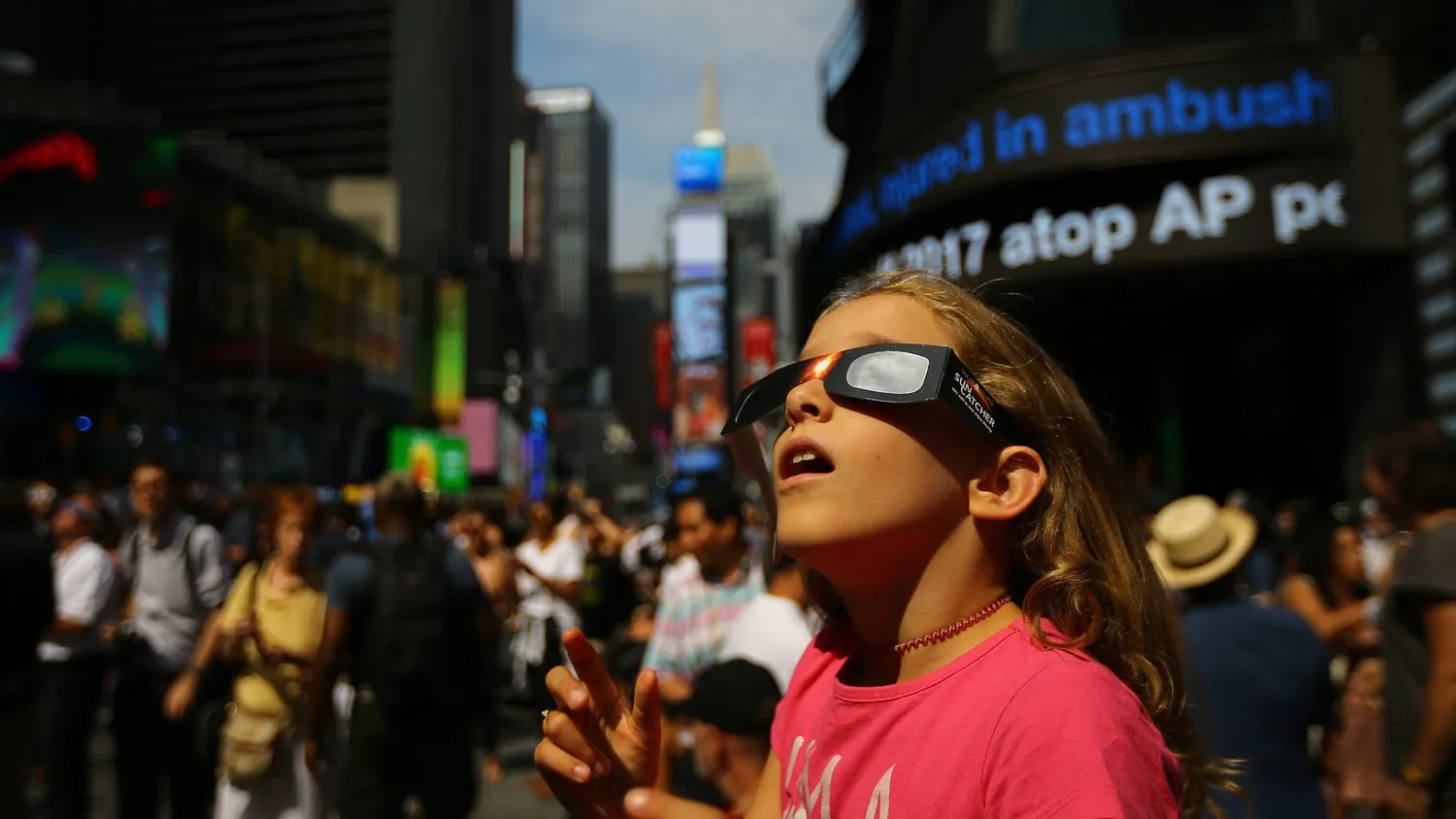 Ein Mädchen beobachtet die totale Sonnenfinsternis mit einer Sonnenfinsternisbrille am Times Square in New York City, Vereinigte Staaten, am 21. August 2017.