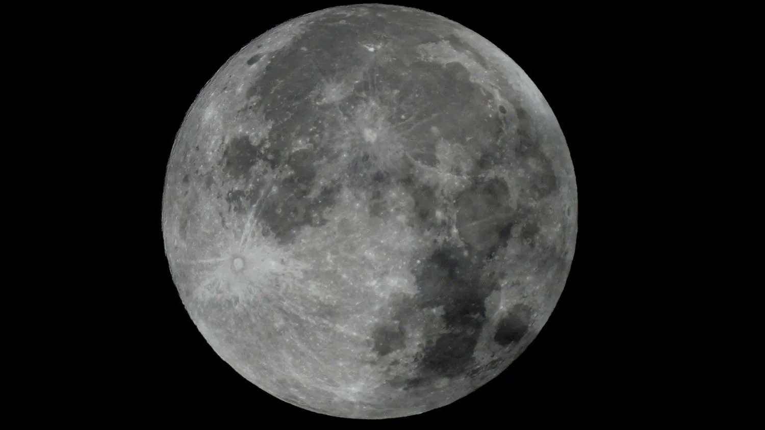 eine Seite der silbrig-grauen Oberfläche des Mondes ist durch einen Schatten leicht verdunkelt